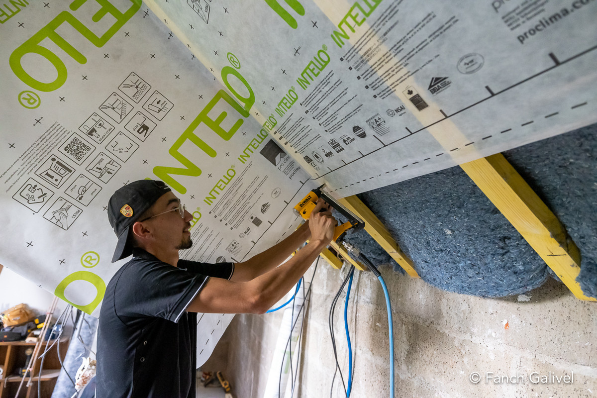 Travaux d’isolation par l’intérieur réalisés par l'entreprise Ty’iso à Camors. Positionnement d'un pare-vapeur après placage d’une laine de coton en 2 couches croisées sur les rampants.