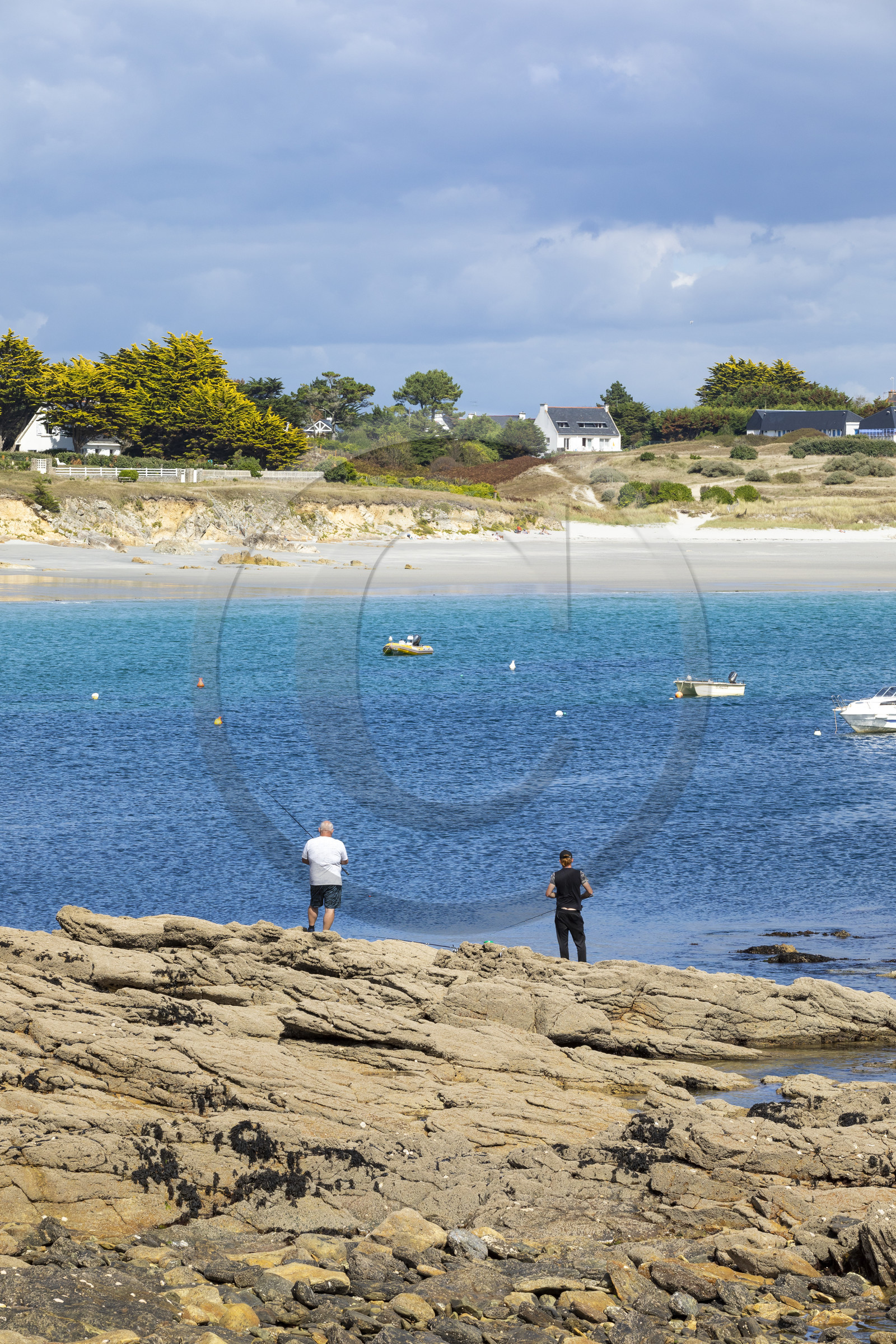Pêcheur sur la pointe de Kerjean sur la commune de Trégunc. En arrière-plan, la plage de Kersidan